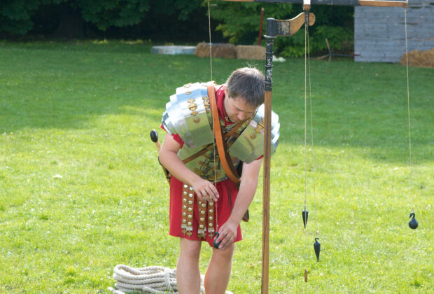 A modern reconstruction of a Roman groma, showing crossed arms and suspended plumb lines.