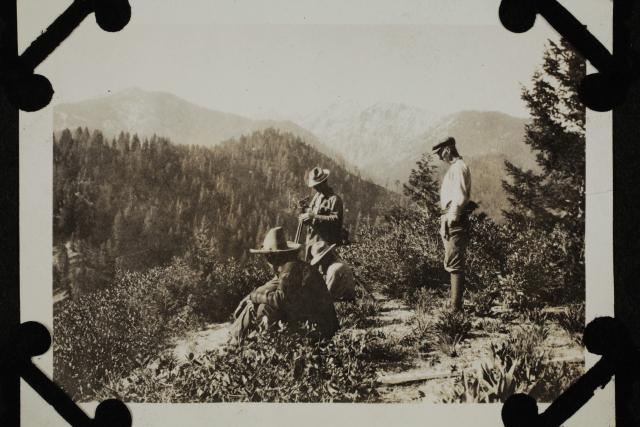 Historical photograph of a General Land Office surveying crew on a rocky, forested hillside in 1924.
