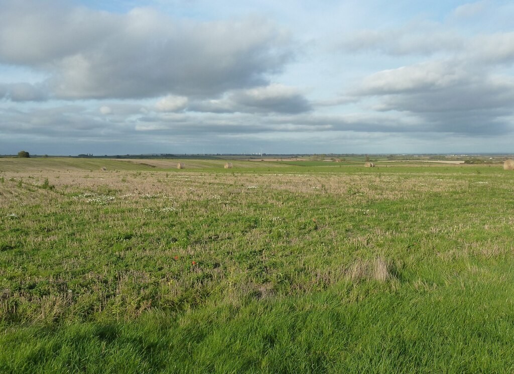 Broad fields at Laxton in Nottinghamshire under a cloudy sky, with cut vegetation and scattered bales.