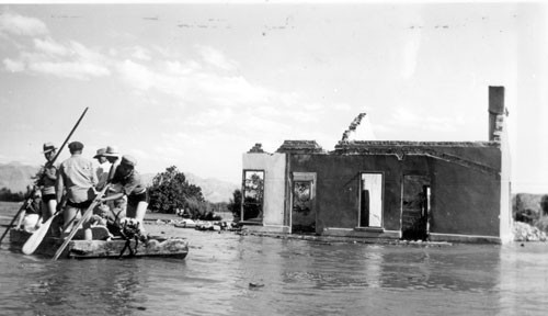 Black-and-white photograph of several men on a raft beside a partly submerged building in St. Thomas in 1938.